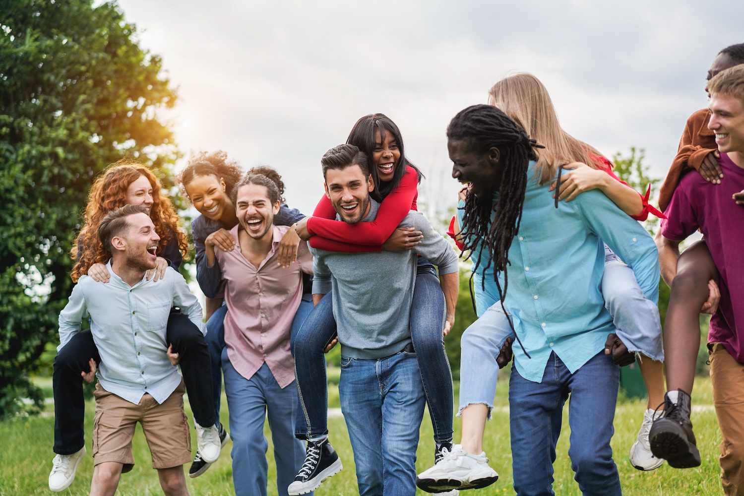 Young diverse friends having fun outdoor laughing together - Focus on center african girl face