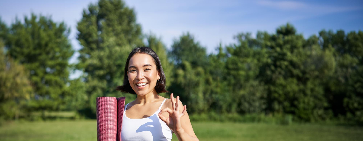 Excited-young-woman-standing-with-sports-mat